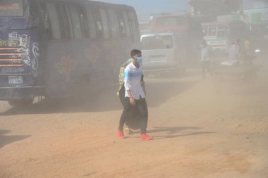 12 Kasım 2020 'de Bangladeş' in Dhaka kentindeki tozlu bir yolda insanlar yürür. Dhaka şehrinin kliması, şehrin pek çok kesimindeki yeni yol inşaatları nedeniyle son iki yıldır endişe verici bir hızla günden güne kötüleşiyor..
