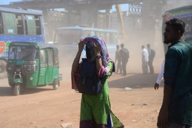 12 Kasım 2020 'de Bangladeş' in Dhaka kentindeki tozlu bir yolda insanlar yürür. Dhaka şehrinin kliması, şehrin pek çok kesimindeki yeni yol inşaatları nedeniyle son iki yıldır endişe verici bir hızla günden güne kötüleşiyor..