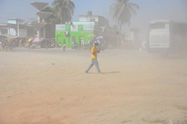 12 Kasım 2020 'de Bangladeş' in Dhaka kentindeki tozlu bir yolda insanlar yürür. Dhaka şehrinin kliması, şehrin pek çok kesimindeki yeni yol inşaatları nedeniyle son iki yıldır endişe verici bir hızla günden güne kötüleşiyor..