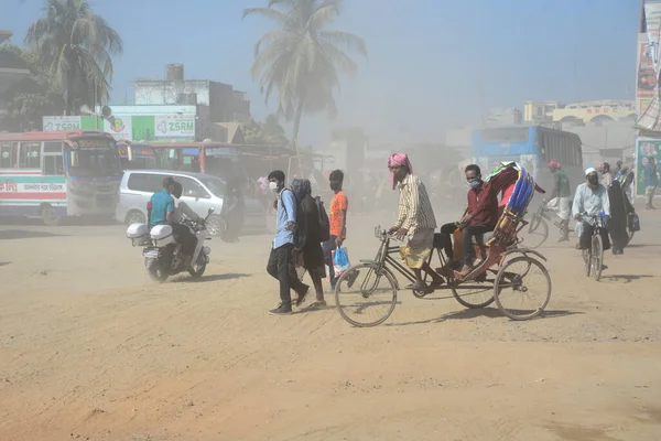 12 Kasım 2020 'de Bangladeş' in Dhaka kentindeki tozlu bir yolda insanlar yürür. Dhaka şehrinin kliması, şehrin pek çok kesimindeki yeni yol inşaatları nedeniyle son iki yıldır endişe verici bir hızla günden güne kötüleşiyor..