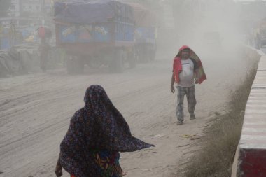 25 Kasım 2020 'de Bangladeş' in Dhaka kentindeki tozlu bir yolda insanlar yürür. Dhaka şehrinin kliması, şehrin pek çok kesimindeki yeni yol inşaatları nedeniyle son iki yıldır endişe verici bir hızla günden güne kötüleşiyor..