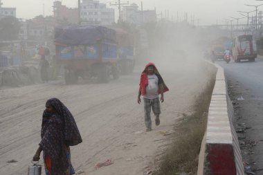 25 Kasım 2020 'de Bangladeş' in Dhaka kentindeki tozlu bir yolda insanlar yürür. Dhaka şehrinin kliması, şehrin pek çok kesimindeki yeni yol inşaatları nedeniyle son iki yıldır endişe verici bir hızla günden güne kötüleşiyor..
