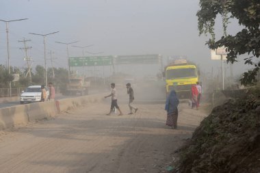 25 Kasım 2020 'de Bangladeş' in Dhaka kentindeki tozlu bir yolda insanlar yürür. Dhaka şehrinin kliması, şehrin pek çok kesimindeki yeni yol inşaatları nedeniyle son iki yıldır endişe verici bir hızla günden güne kötüleşiyor..
