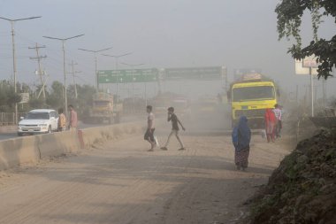 25 Kasım 2020 'de Bangladeş' in Dhaka kentindeki tozlu bir yolda insanlar yürür. Dhaka şehrinin kliması, şehrin pek çok kesimindeki yeni yol inşaatları nedeniyle son iki yıldır endişe verici bir hızla günden güne kötüleşiyor..