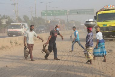 25 Kasım 2020 'de Bangladeş' in Dhaka kentindeki tozlu bir yolda insanlar yürür. Dhaka şehrinin kliması, şehrin pek çok kesimindeki yeni yol inşaatları nedeniyle son iki yıldır endişe verici bir hızla günden güne kötüleşiyor..