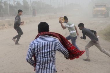 25 Kasım 2020 'de Bangladeş' in Dhaka kentindeki tozlu bir yolda insanlar yürür. Dhaka şehrinin kliması, şehrin pek çok kesimindeki yeni yol inşaatları nedeniyle son iki yıldır endişe verici bir hızla günden güne kötüleşiyor..