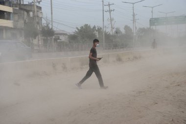 25 Kasım 2020 'de Bangladeş' in Dhaka kentindeki tozlu bir yolda insanlar yürür. Dhaka şehrinin kliması, şehrin pek çok kesimindeki yeni yol inşaatları nedeniyle son iki yıldır endişe verici bir hızla günden güne kötüleşiyor..