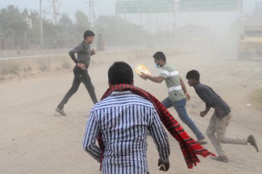 25 Kasım 2020 'de Bangladeş' in Dhaka kentindeki tozlu bir yolda insanlar yürür. Dhaka şehrinin kliması, şehrin pek çok kesimindeki yeni yol inşaatları nedeniyle son iki yıldır endişe verici bir hızla günden güne kötüleşiyor..