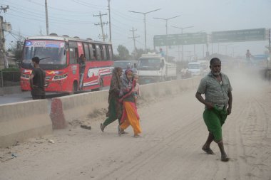25 Kasım 2020 'de Bangladeş' in Dhaka kentindeki tozlu bir yolda insanlar yürür. Dhaka şehrinin kliması, şehrin pek çok kesimindeki yeni yol inşaatları nedeniyle son iki yıldır endişe verici bir hızla günden güne kötüleşiyor..