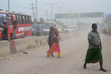 25 Kasım 2020 'de Bangladeş' in Dhaka kentindeki tozlu bir yolda insanlar yürür. Dhaka şehrinin kliması, şehrin pek çok kesimindeki yeni yol inşaatları nedeniyle son iki yıldır endişe verici bir hızla günden güne kötüleşiyor..