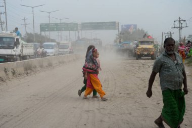 25 Kasım 2020 'de Bangladeş' in Dhaka kentindeki tozlu bir yolda insanlar yürür. Dhaka şehrinin kliması, şehrin pek çok kesimindeki yeni yol inşaatları nedeniyle son iki yıldır endişe verici bir hızla günden güne kötüleşiyor..