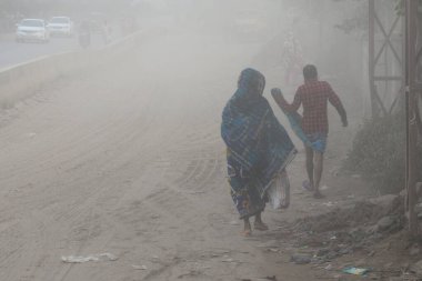 25 Kasım 2020 'de Bangladeş' in Dhaka kentindeki tozlu bir yolda insanlar yürür. Dhaka şehrinin kliması, şehrin pek çok kesimindeki yeni yol inşaatları nedeniyle son iki yıldır endişe verici bir hızla günden güne kötüleşiyor..