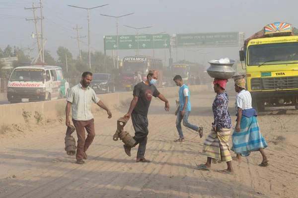 25 Kasım 2020 'de Bangladeş' in Dhaka kentindeki tozlu bir yolda insanlar yürür. Dhaka şehrinin kliması, şehrin pek çok kesimindeki yeni yol inşaatları nedeniyle son iki yıldır endişe verici bir hızla günden güne kötüleşiyor..