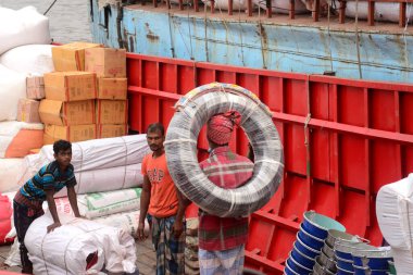 Bangladeşli işçiler, 6 Aralık 2020 'de Dhaka, Bangladeş' teki COVID-19 koronavirüs salgını sırasında kargo botlarını yüklemek için kafalarında mal taşıyorlar.