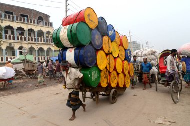 Bangladeşli işçi, 6 Aralık 2020 'de Bangladeş' in Dhaka kentindeki COVID-19 Coronavirüs salgınının ortasında el arabasının yanında boş varil taşıyor.