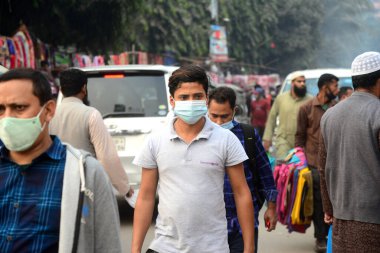 23 Aralık 2020 'de Dhaka, Bangladeş' teki Covid-19 Coronavirus salgınının ortasında yüz maskesi takan insanlar sokakta yürür..