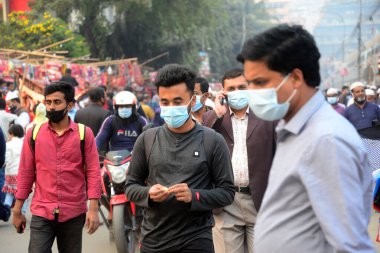 23 Aralık 2020 'de Dhaka, Bangladeş' teki Covid-19 Coronavirus salgınının ortasında yüz maskesi takan insanlar sokakta yürür..
