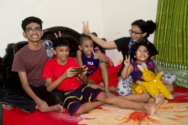 2 Ocak 2021 'de Dhaka, Bangladeş' teki COVID-19 Coronavirus salgını sırasında evlerinde oyun oynamak için cep telefonu kullanan çocuklar