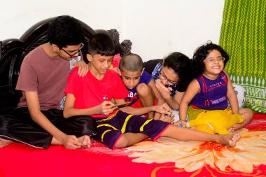 2 Ocak 2021 'de Dhaka, Bangladeş' teki COVID-19 Coronavirus salgını sırasında evlerinde oyun oynamak için cep telefonu kullanan çocuklar