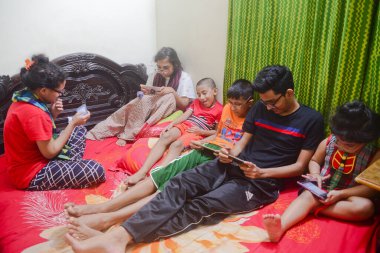 2 Ocak 2021 'de Dhaka, Bangladeş' teki COVID-19 Coronavirus salgını sırasında evlerinde oyun oynamak için cep telefonu kullanan çocuklar