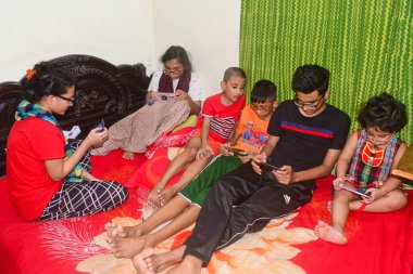 2 Ocak 2021 'de Dhaka, Bangladeş' teki COVID-19 Coronavirus salgını sırasında evlerinde oyun oynamak için cep telefonu kullanan çocuklar