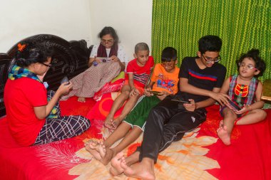 2 Ocak 2021 'de Dhaka, Bangladeş' teki COVID-19 Coronavirus salgını sırasında evlerinde oyun oynamak için cep telefonu kullanan çocuklar