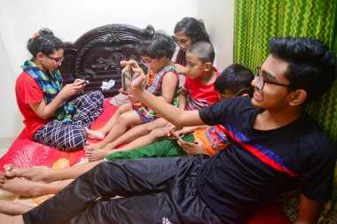 2 Ocak 2021 'de Dhaka, Bangladeş' teki COVID-19 Coronavirus salgını sırasında evlerinde oyun oynamak için cep telefonu kullanan çocuklar