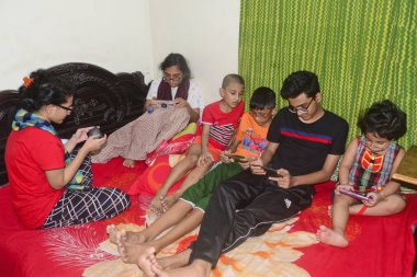 2 Ocak 2021 'de Dhaka, Bangladeş' teki COVID-19 Coronavirus salgını sırasında evlerinde oyun oynamak için cep telefonu kullanan çocuklar