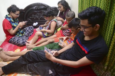 2 Ocak 2021 'de Dhaka, Bangladeş' teki COVID-19 Coronavirus salgını sırasında evlerinde oyun oynamak için cep telefonu kullanan çocuklar