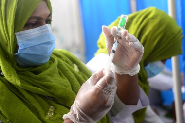 7 Şubat 2021 'de Dhaka, Bangladeş' te, ülkenin dört bir yanında aşılama başladığında Sheikh Russell Ulusal Gastro Karaciğer Enstitüsü 'nde üretilen COVID-19 aşısını hazırlayan bir sağlık çalışanı