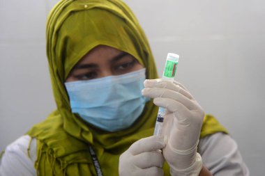 7 Şubat 2021 'de Dhaka, Bangladeş' te, ülkenin dört bir yanında aşılama başladığında Sheikh Russell Ulusal Gastro Karaciğer Enstitüsü 'nde üretilen COVID-19 aşısını hazırlayan bir sağlık çalışanı