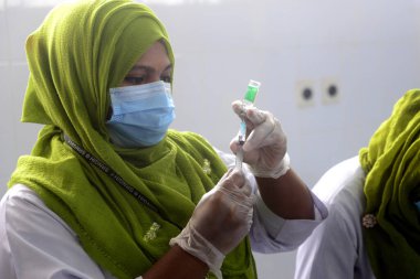 7 Şubat 2021 'de Dhaka, Bangladeş' te, ülkenin dört bir yanında aşılama başladığında Sheikh Russell Ulusal Gastro Karaciğer Enstitüsü 'nde üretilen COVID-19 aşısını hazırlayan bir sağlık çalışanı