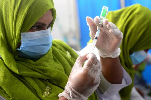 7 Şubat 2021 'de Dhaka, Bangladeş' te, ülkenin dört bir yanında aşılama başladığında Sheikh Russell Ulusal Gastro Karaciğer Enstitüsü 'nde üretilen COVID-19 aşısını hazırlayan bir sağlık çalışanı