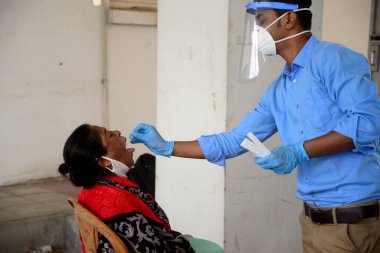 Bir sağlık çalışanı, 21 Mart 2021 tarihinde Bangladeş, Dhaka 'daki Mugda Tıp Fakültesi ve Hastanesi' nde COVID-19 Coronavirüs testi için bir insandan örnek alır..