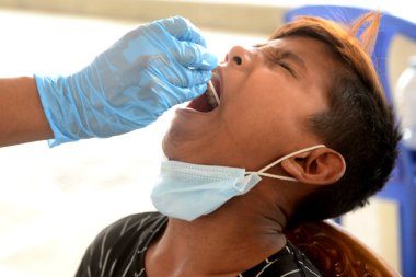 Bir sağlık çalışanı, 21 Mart 2021 tarihinde Bangladeş, Dhaka 'daki Mugda Tıp Fakültesi ve Hastanesi' nde COVID-19 Coronavirüs testi için bir insandan örnek alır..