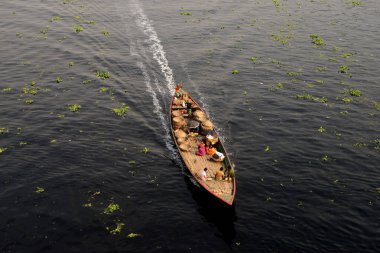 İnsanlar 21 Mart 2021 'de Dhaka, Bangladeş' teki kirlenmiş Buriganga Nehri 'nin zifiri karanlık sularından tekneyle geçiyorlar. Bangladeş 'in endüstriyel atıklar nedeniyle dünyanın ilk 20 plastik kirleticisi arasında 10. sırada yer aldığı bildiriliyor.