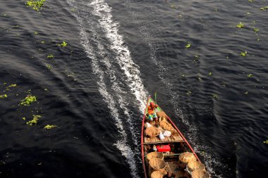 İnsanlar 21 Mart 2021 'de Dhaka, Bangladeş' teki kirlenmiş Buriganga Nehri 'nin zifiri karanlık sularından tekneyle geçiyorlar. Bangladeş 'in endüstriyel atıklar nedeniyle dünyanın ilk 20 plastik kirleticisi arasında 10. sırada yer aldığı bildiriliyor.