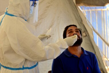 Bir sağlık çalışanı, 23 Mart 2021 tarihinde Bangladeş 'in Dhaka kentindeki Shaheed Suhrawardy Tıp Fakültesi & Hastanesi' nde COVID-19 Coronavirüs testi için bir insandan örnek alır.