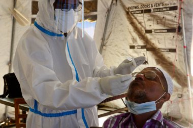 Bir sağlık çalışanı, 23 Mart 2021 tarihinde Bangladeş 'in Dhaka kentindeki Shaheed Suhrawardy Tıp Fakültesi & Hastanesi' nde COVID-19 Coronavirüs testi için bir insandan örnek alır.