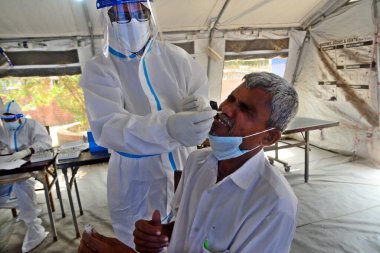 Bir sağlık çalışanı, 23 Mart 2021 tarihinde Bangladeş 'in Dhaka kentindeki Shaheed Suhrawardy Tıp Fakültesi & Hastanesi' nde COVID-19 Coronavirüs testi için bir insandan örnek alır.