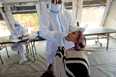 Bir sağlık çalışanı, 23 Mart 2021 tarihinde Bangladeş 'in Dhaka kentindeki Shaheed Suhrawardy Tıp Fakültesi & Hastanesi' nde COVID-19 Coronavirüs testi için bir insandan örnek alır.