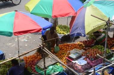 İnsanlar, Bangladeş yetkilileri, 15 Nisan 2021 'de Bangladeş' in Dhaka kentindeki Covid-19 Coronavirüsünün yayılmasını önlemek için ihtiyaçlarını satın almak için meyve pazarında toplandılar.