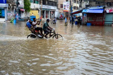Vatandaşlar ve araçlar 1 Haziran 2021 'de sağanak yağış neredeyse durgunluğa yol açtıktan sonra Dhaka' nın sulak caddelerinde ilerlemeye çalışırlar. Muson yağmurlarının ardından Bangladeş 'in başkenti Dhaka' daki bölgenin çoğu sular altında kaldı..