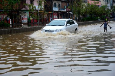 Vatandaşlar ve araçlar 1 Haziran 2021 'de sağanak yağış neredeyse durgunluğa yol açtıktan sonra Dhaka' nın sulak caddelerinde ilerlemeye çalışırlar. Muson yağmurlarının ardından Bangladeş 'in başkenti Dhaka' daki bölgenin çoğu sular altında kaldı..