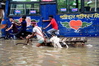 Vatandaşlar ve araçlar 1 Haziran 2021 'de sağanak yağış neredeyse durgunluğa yol açtıktan sonra Dhaka' nın sulak caddelerinde ilerlemeye çalışırlar. Muson yağmurlarının ardından Bangladeş 'in başkenti Dhaka' daki bölgenin çoğu sular altında kaldı..