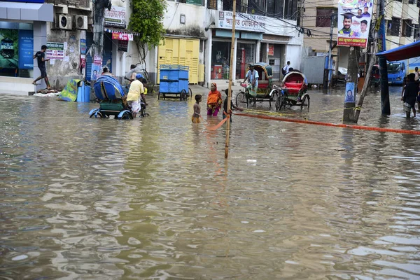 Vatandaşlar ve araçlar 1 Haziran 2021 'de sağanak yağış neredeyse durgunluğa yol açtıktan sonra Dhaka' nın sulak caddelerinde ilerlemeye çalışırlar. Muson yağmurlarının ardından Bangladeş 'in başkenti Dhaka' daki bölgenin çoğu sular altında kaldı..
