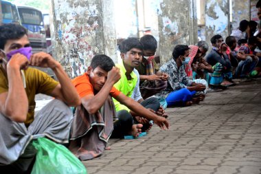4 Temmuz 2021 'de Dhaka' daki Gabtali otobüs terminalinde Covid-19 koronavirüsünün yayılmasını kontrol altına almak için uygulanan tecrit sırasında evsiz insanlar yiyecek yardımı bekliyor.