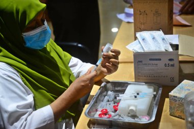 Bir sağlık çalışanı 24 Temmuz 202 'de Bangladeş, Dhaka' daki hastanede Covid-19 koronavirüsüne karşı bir doz Moderna aşısı olan bir adamı aşıladı.