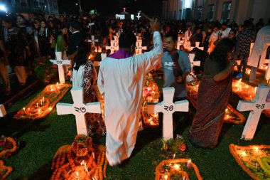 Hıristiyan fanatikler, 2 Kasım 2025 tarihinde Bangladeş 'in Dhaka kentindeki Tejgaon Kutsal Haç Kilisesi Mezarlığı' ndaki Ruhlar Günü kutlamaları sırasında akrabalarının mezarlarında mum yakarlar.
