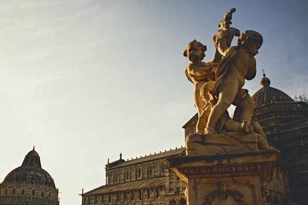 Крупный план маленьких ангельских скульптур в комплексе Пиза, теплые золотые тона, резные каменные детали, итальянское искусство, наследие, декоративная архитектура, Тоскана, историческая атмосфера.